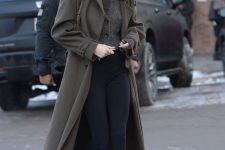 Kendall Jenner wearing a taupe turtleneck, a grey cardigan, black leggings, black boots and a grey green midi coat