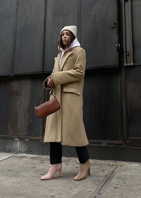 With beige hat, black trousers, brown leather bag and beige and pale pink leather boots