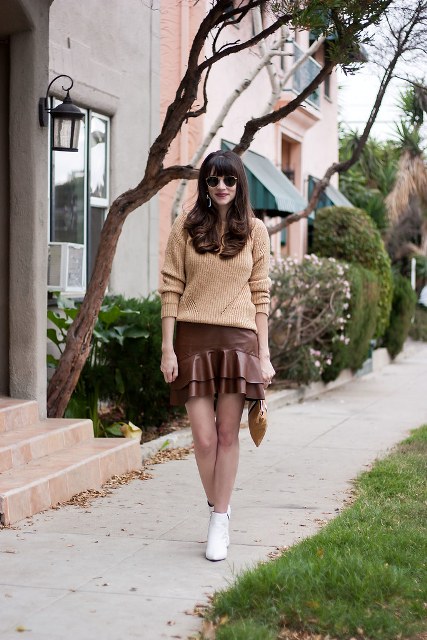 With beige loose sweater, rounded sunglasses, brown clutch and white ankle boots