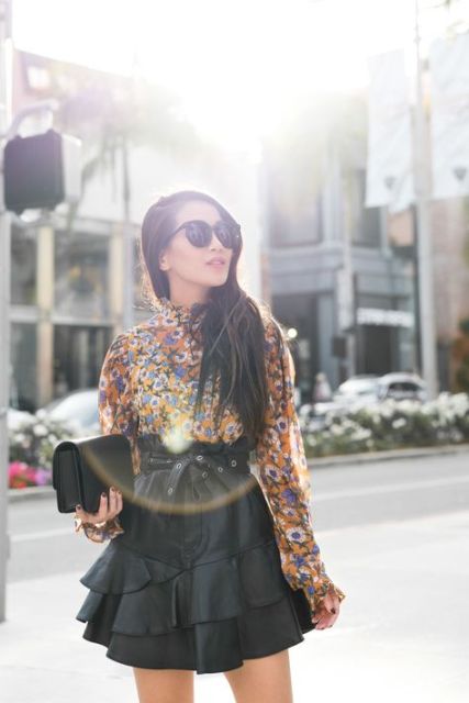 With colorful floral printed long sleeved blouse, oversized sunglasses and black leather clutch