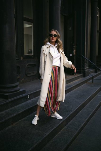 With colorful striped pleated asymmetrical midi skirt, sunglasses and white sneakers