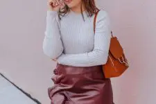 With gray fitted sweater, brown leather and suede bag and oversized sunglasses