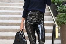 With navy blue loose V-neck sweater, black tote bag, oversized sunglasses and black patent leather pumps