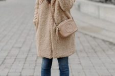 With skinny cropped jeans, sunglasses, white high heel boots, beige leather tassel crossbody bag and black hat with a blue pom pom