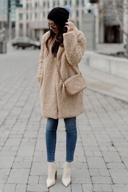 With skinny cropped jeans, sunglasses, white high heel boots, beige leather tassel crossbody bag and black hat with a blue pom pom