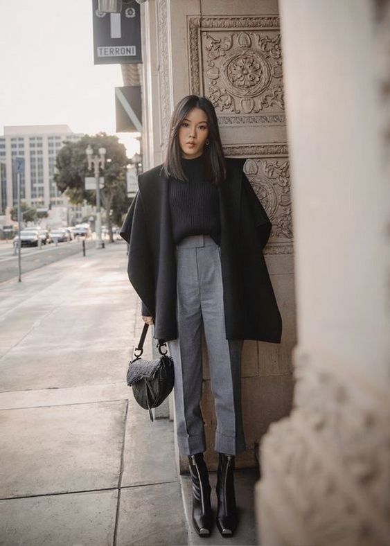 a black ribbed jumper, grey cropped trousers, black zip boots, a black coat and a catchy black bag