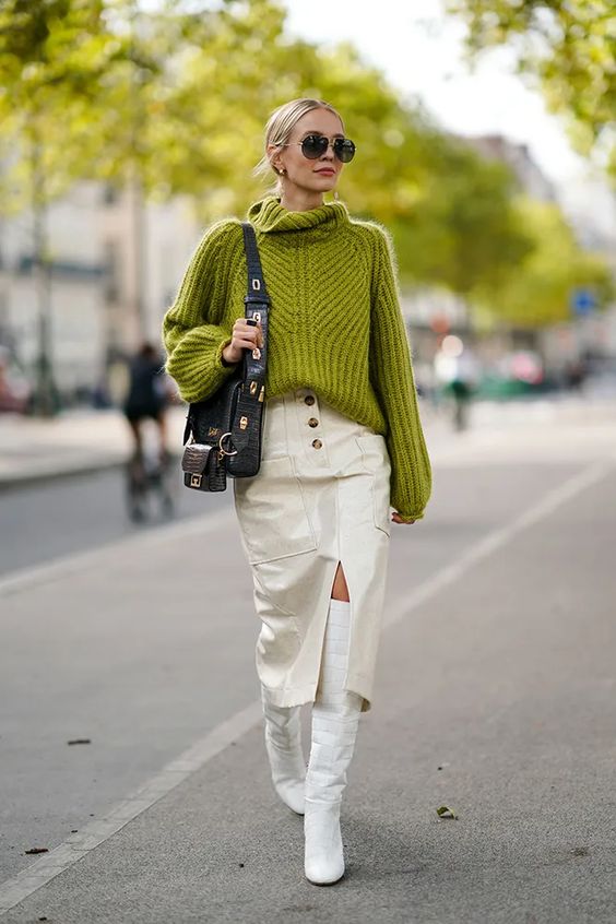 a bold and super trendy winter work look with a green chunky sweater, a white leather midi skirt with pockets, white tall boots and a black bag