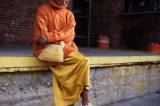 a bright outfit with an oversized orange braided sweater, a mellow yellow slip skirt, white trainers and an embellished bag