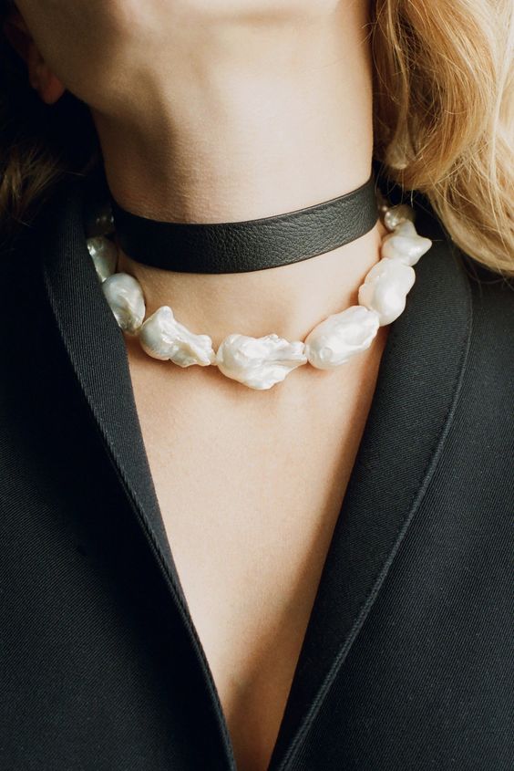 a large baroque pearl choker paired with a black leather one creates a bold contrasting look that will catch all the eyes