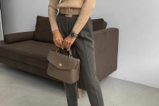 a lovely and laconic winter work look with a beige turtleneck sweater, grey trousers, dove grey boots, a grey bag and a statement belt