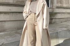 a minimalist neutral winter outfit with a grey turtleneck sweater, tan high waisted pants, white boots and a white coat