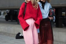 a red oversized braided sweater, pink high waisted trousers and a black bag plus black boots