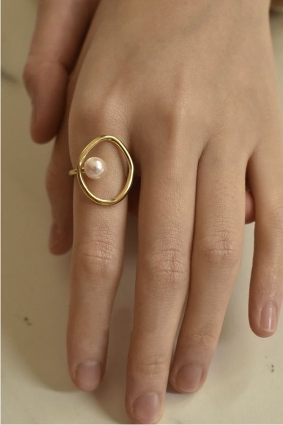 a statement yet subtle gold ring of an irregular shape but with a regular-shaped pearl is a gorgeous solution for your look