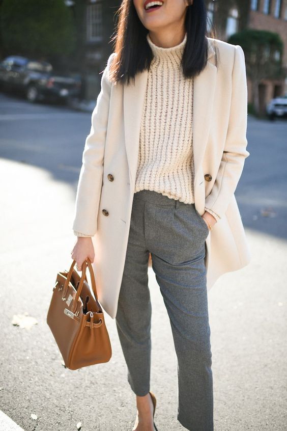 a stylish and elegant winter work outfit with a white chunky sweater, grey trousers, a creamy oversized blazer and a brown bag