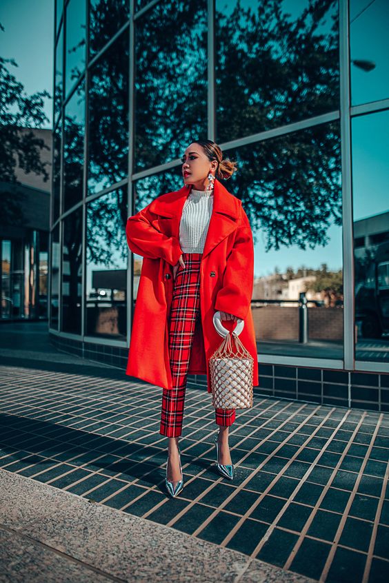 a white jumper, red plaid trousers, silver shoes, a red midi coat, a bucket bag and statement earrings