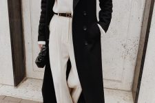 a white sweater, white trousers with a black belt, black boots, a black maxi coat and a black clutch for a minimalist monochromatic look