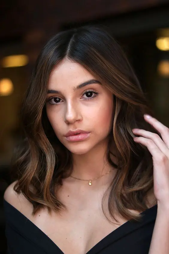 almost black wavy long bob with super delicate and subtle caramel highlights including face-framing ones for a bolder look
