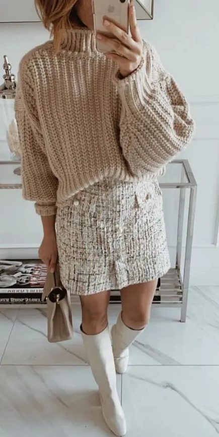 an all-neutral outfit with a creamy oversized chunky jumper, a white tweed mini, white knee boots and a grey mini bag