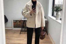an elegant and minimalist winter work outfit with a black turtleneck, black trousers, boots, a creamy shirt coat and a burgundy bag