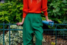 an orange sweater with puff sleeves, green high-waisted trousers, green shoes and a light blue bag for a festive feel