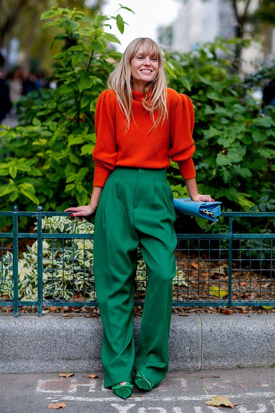 an orange sweater with puff sleeves, green high-waisted trousers, green shoes and a light blue bag for a festive feel