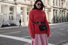 an oversized coral red sweater, a pink asymmetrical skirt, black booties and socks, a black bag