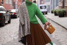 an oversized green turtleneck sweater, a brown pleated midi, green tights, white sneakers and a brown bag
