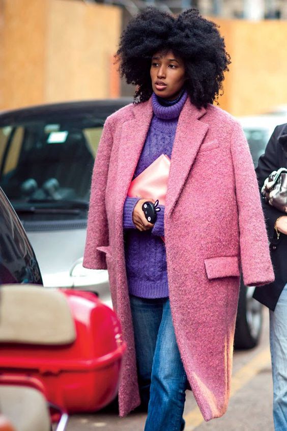 an oversized purple patterned turtleneck sweater, blue jeans, a pink coat and a blush clutch