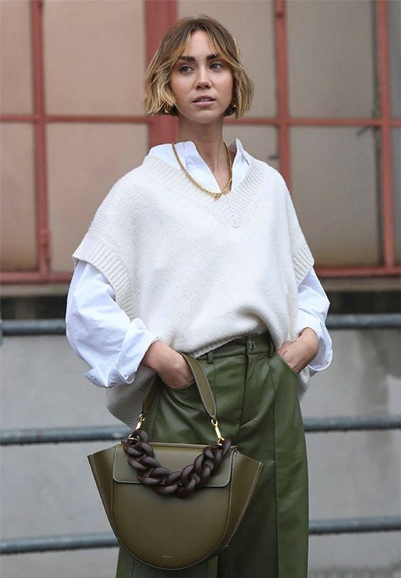 an oversized white shirt, an oversized creamy waistcoat, green leather trousers, a green bag with a statement chain