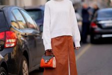 an oversized white sweater, an amber A-line leather skirt, white boots and a two tone bag for a chic winter look