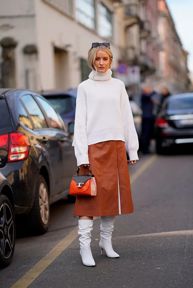 an oversized white sweater, an amber A line leather skirt, white boots and a two tone bag for a chic winter look