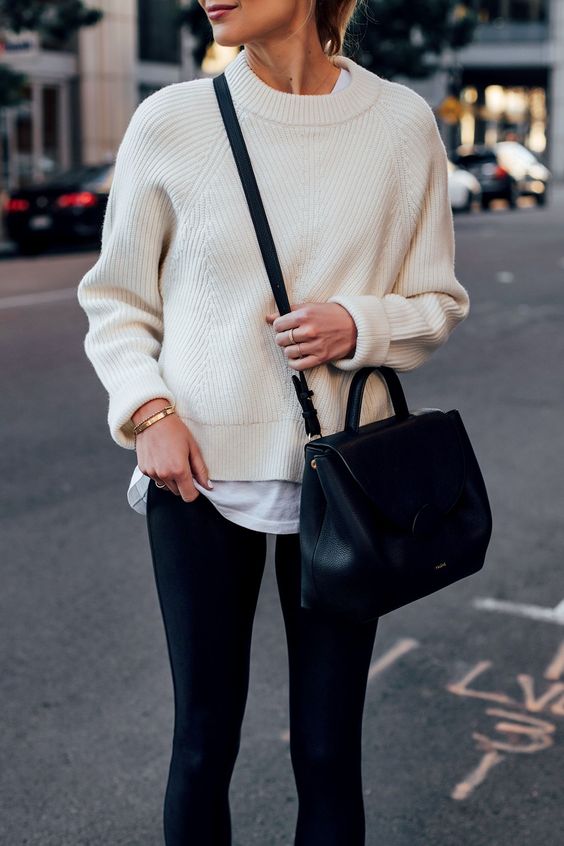 an oversized white t-shirt, a creamy jumper over it, black leggigns and a comfotable black bag