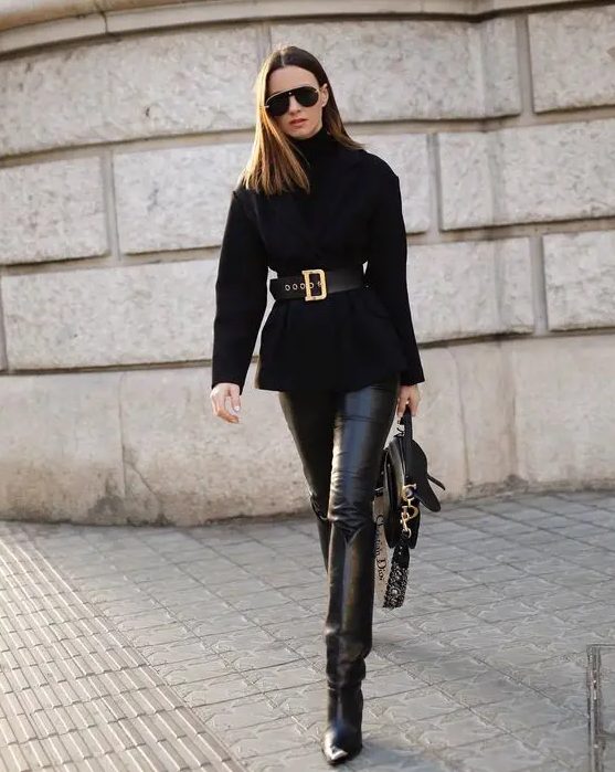 black leather leggings, wide tall boots, an oversized tuterleneck sweater with a wide belt and a black bag