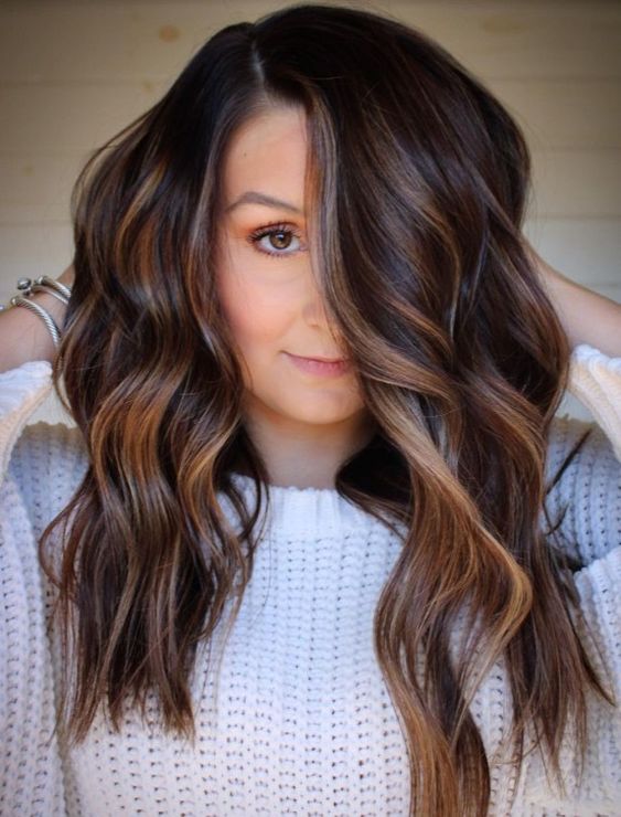 dark chestnut brown hair with waves and with delicate and subtle caramel balayage that highlights the chestnut shade and makes it bolder