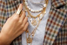layered necklaces including usual and chunky chains, coins, baroque pearls and usual ones paired with a grey t-shirt and a plaid blazer