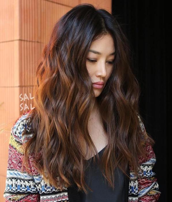 long wavy chocolate brown hair with delicate caramel highlights that give an eye catchy and dimensional touch to the look