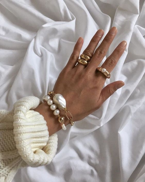 stacked bracelets with regular pearls and an oversized baroque one, stacked gold rings and a gold and pearl ring