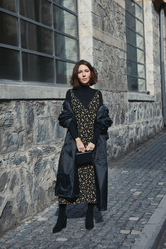 a refined and feminine work look with a black turtleneck, a dark floral slip midi dress, black boots and a black trench plus a bag