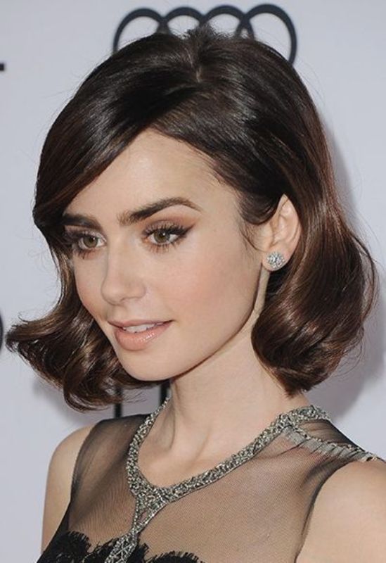Lily Collins rocking a retro-inspired wavy hairstyle with a touch of gloss and creative parting for a super elegant look