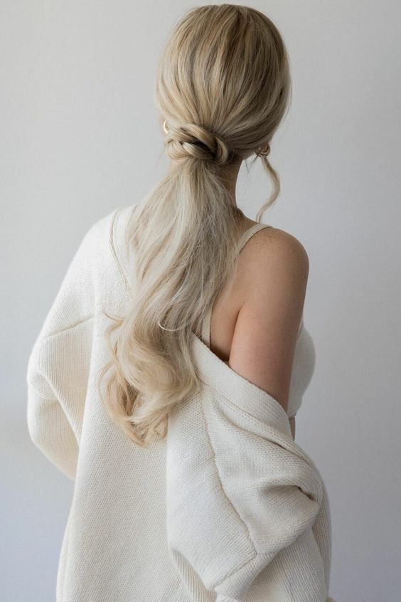 a beautiful wavy low ponytail with a braided wrap and some locks down is a chic idea for a girlish look