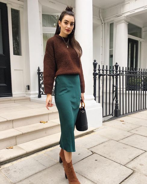 a fall work outfit with a brown jumper, a green slip midi skirt, brown boots and a black bag