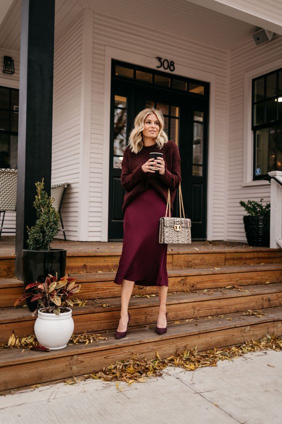 a monochromatic work outfit for the fall, with a deep burgundy sweater, a matching slip midi, matching shoes and a snakeskin print bag