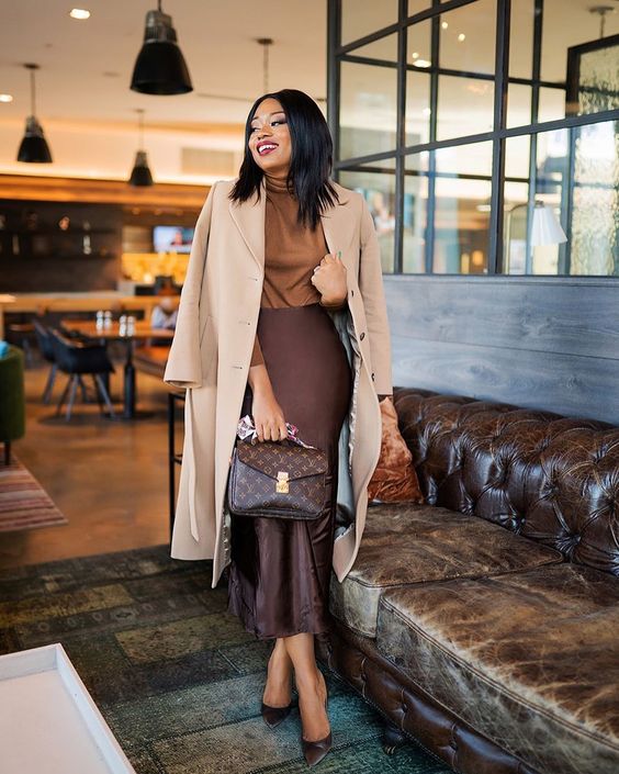 a refined work look with a tust-colored turtleneck, a deep purple slip midi skirt, matching shoes, a neutral coat and a brown bag