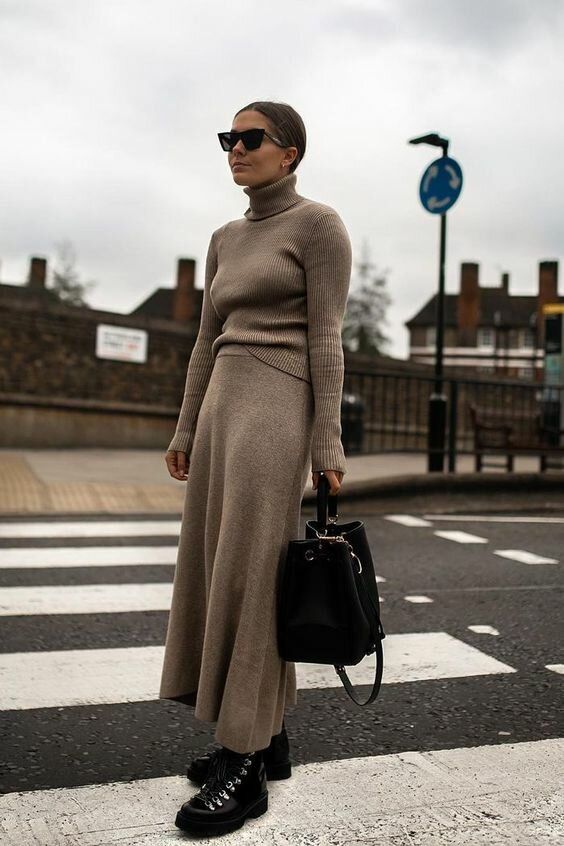 a stylish outfit with a greige turtleneck and a midi skirt, black hiking boots and a large bag for winter