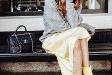 24 a bright spring work outfit with a grey jumper, a bold yellow slip midi skirt, matching boots and a black bag