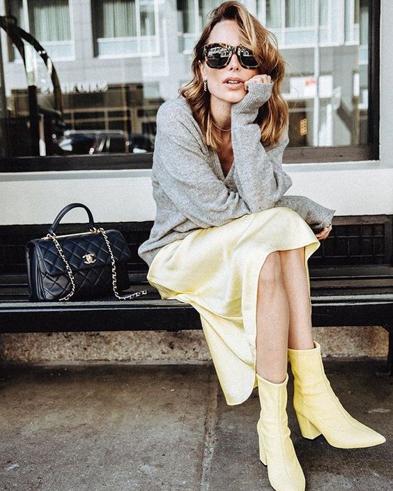 a bright spring work outfit with a grey jumper, a bold yellow slip midi skirt, matching boots and a black bag