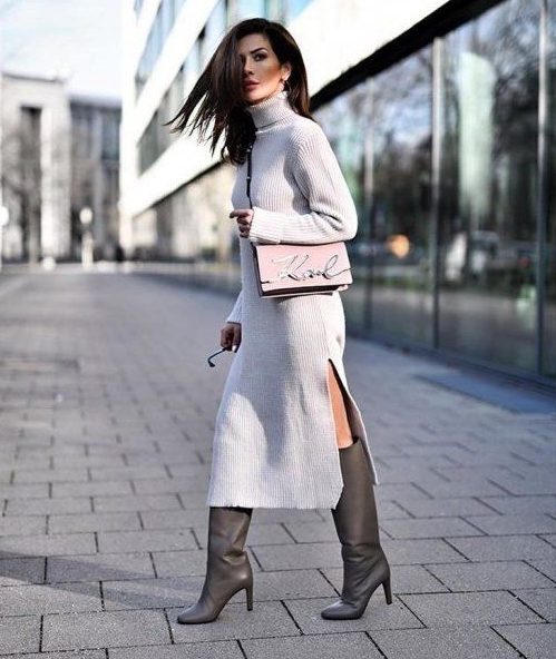 a white knit midi dress with a side slit and a turtleneck, grey wide knee boots and a pink bag