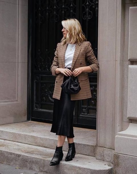 a work outfit with a white tee, a plaid oversized blazer, a black slip midi, black booties
