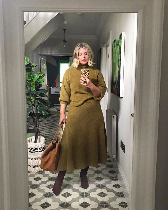 a refined look with a knit set with a moss green sweater and a matching A-line midi skirt, an amber bag and purple boots