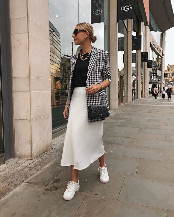 a monochromatic work look with a black t shirt, a white slip midi skirt, white sneakers, a printed black and white blazer and a black bag